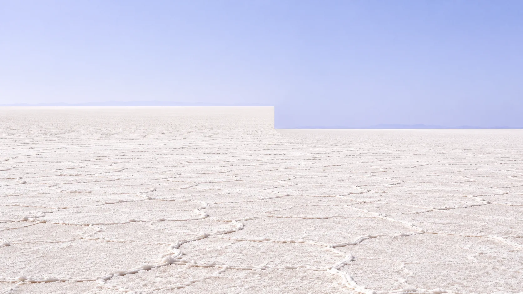 A white salt flat runs to the horizon under a pale sky, and halfway across, the horizon steps down a level like two photos badly joined. Someone will have to come out and fix that.