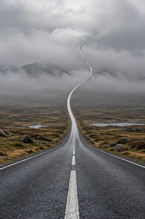 A straight road runs across a grey moor and keeps going, winding up into the clouds and out of sight.